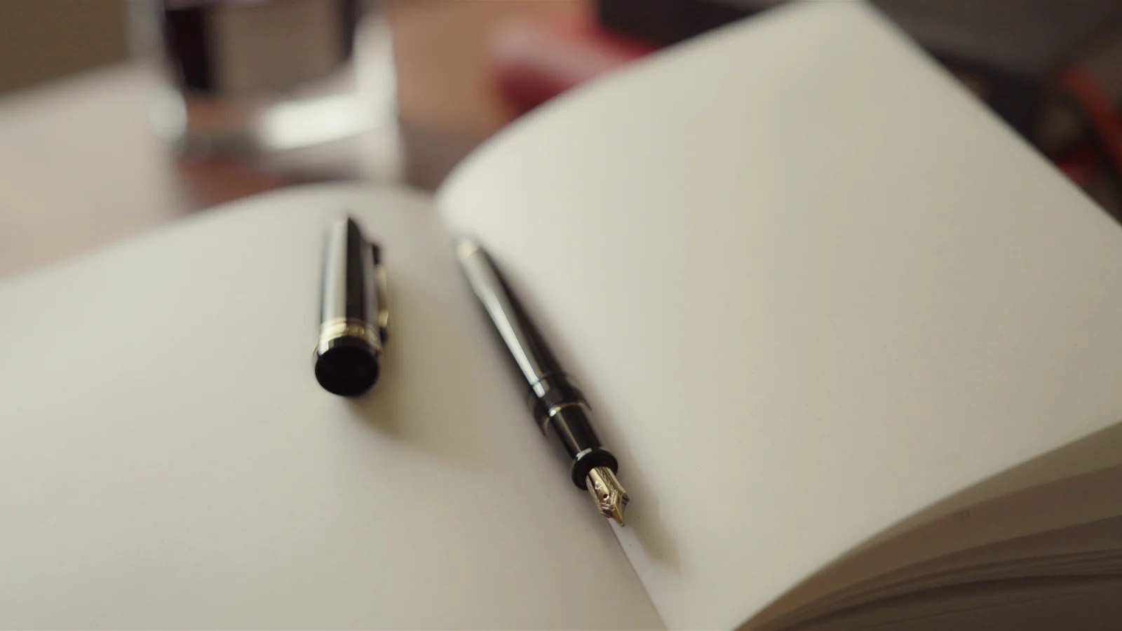 An uncapped fountain pen resting on an open notebook