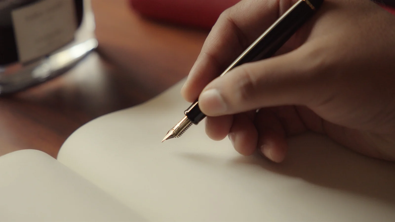 A close-up of a hand writing with a fountain pen